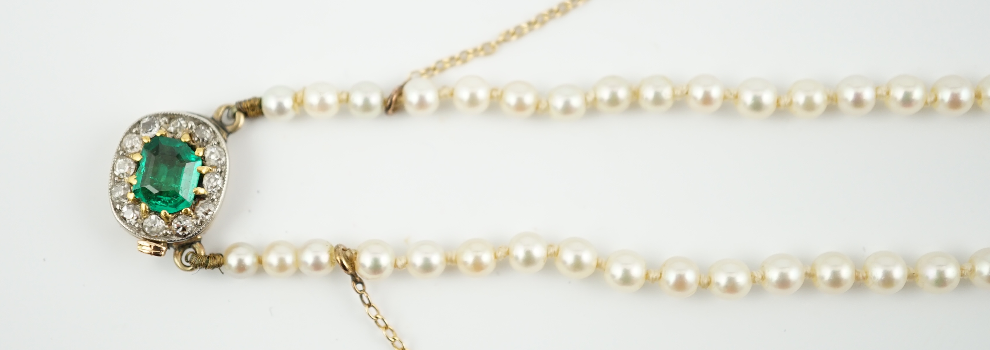 A single strand graduated cultured pearl necklace, with emerald and diamond cluster set gold clasp